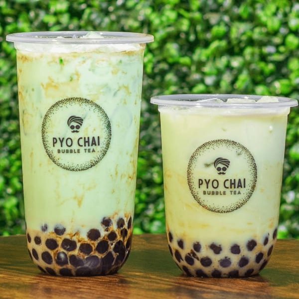 Two PYO CHAI boba drinks, one tall and one short, with tapioca pearls and light green liquid.