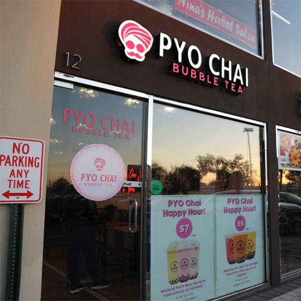 Exterior of PYO Chai bubble tea shop with a "No Parking" sign and happy hour specials.