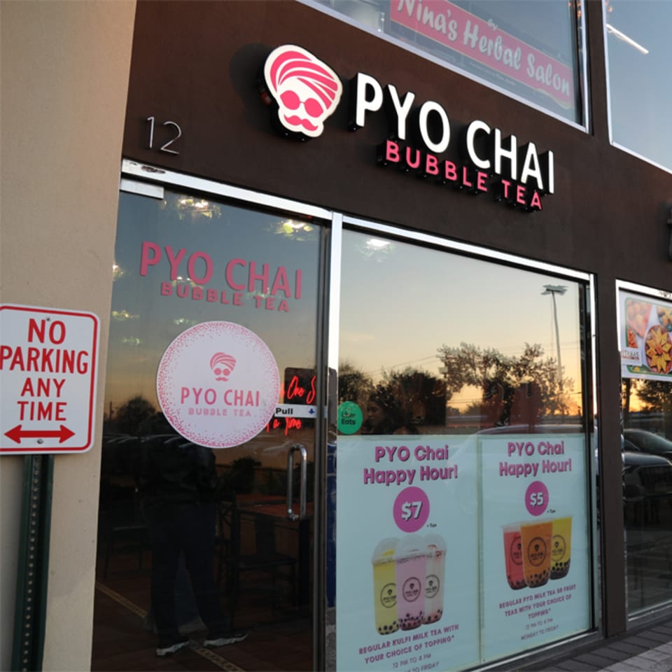 Exterior of PYO Chai bubble tea shop with a "No Parking" sign and happy hour specials.