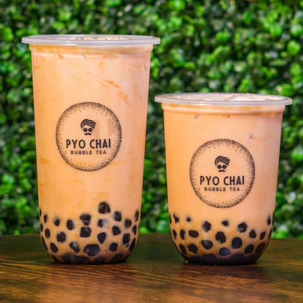 Two PYO Chai bubble teas, one large and one small, filled with boba and a creamy drink.
