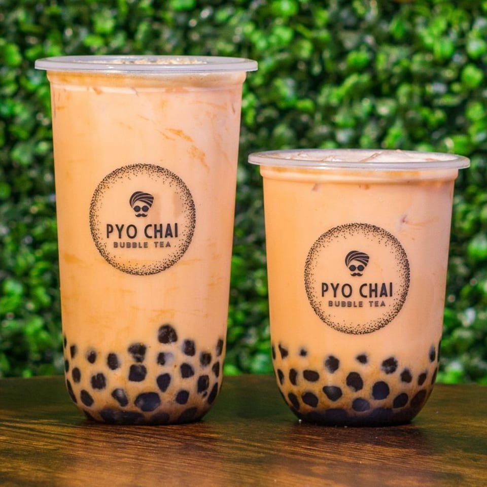 Two PYO Chai bubble teas, one large and one small, filled with boba and a creamy drink.