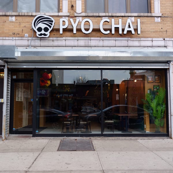 PYO CHAI boba shop exterior with a brick facade, large windows, and a sidewalk.