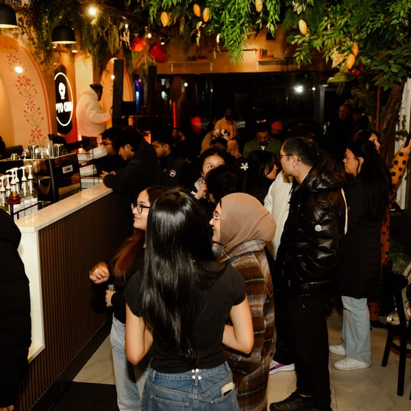 Customers gather at the counter of PYO Chai, a boba tea shop, under warm lighting and lush decor.
