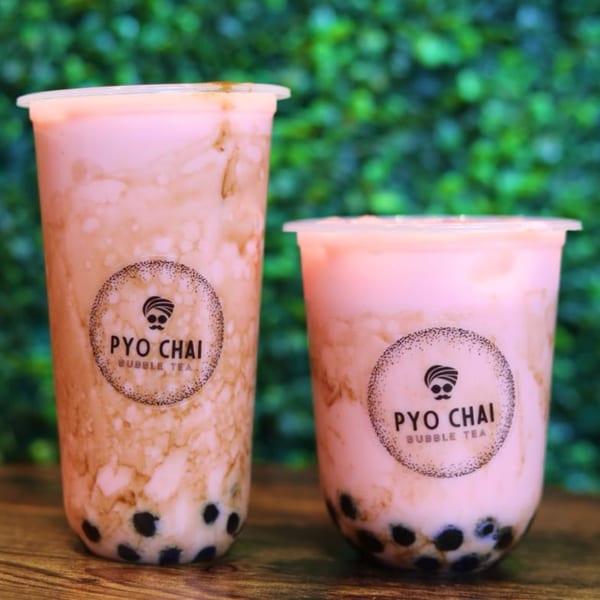 Two PYO Chai boba drinks, one large and one small, with pink liquid and dark boba pearls.
