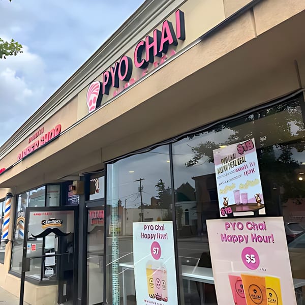Exterior view of PYO Chai boba shop with pink signage and happy hour specials displayed.